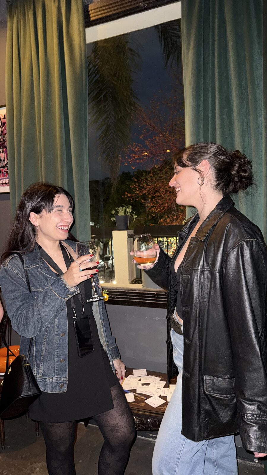 Dos personas riéndose con un trago en mano durante un evento de equipo