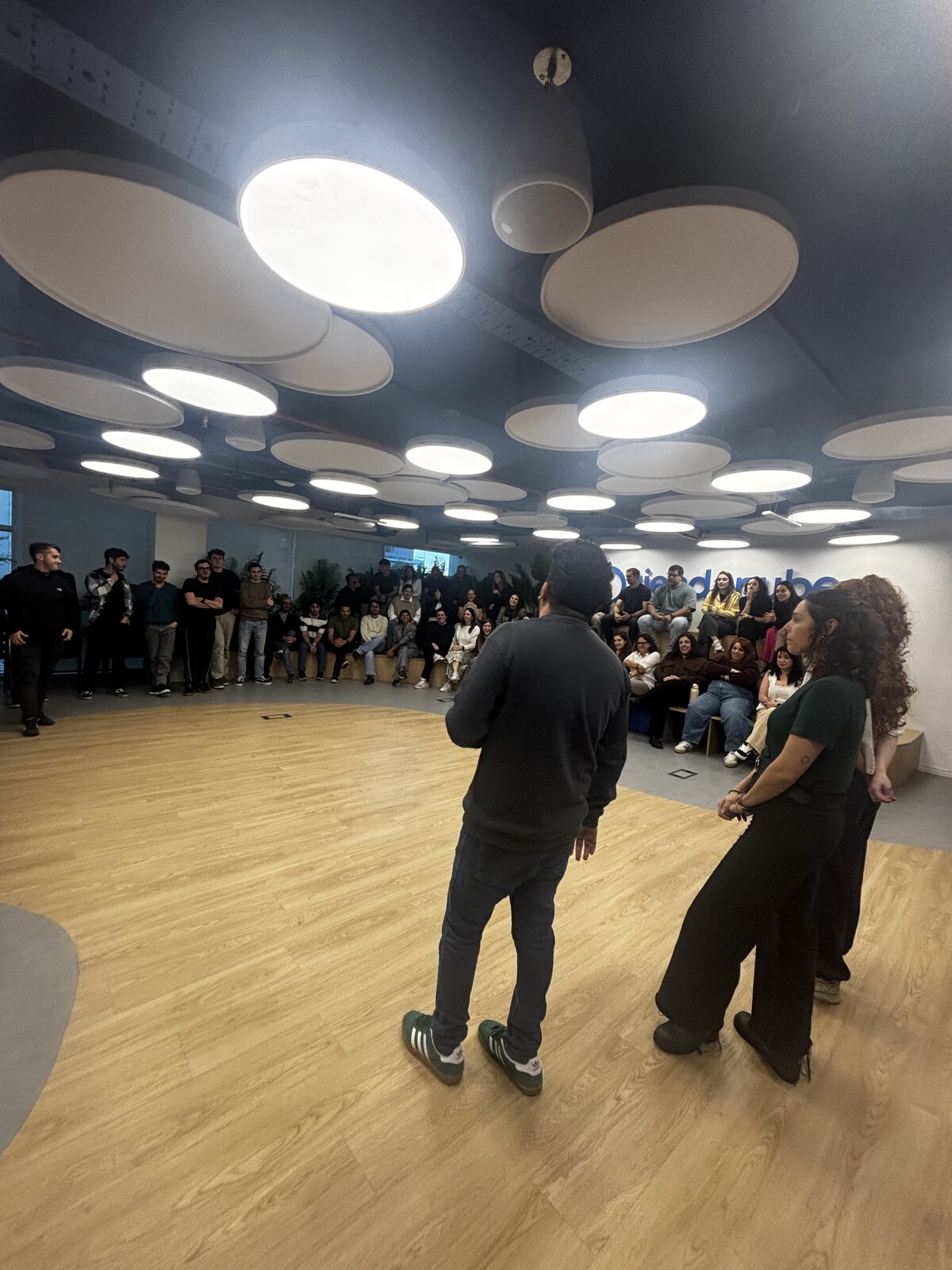Equipo de empresa sentado en gradas de madera escuchando a los facilitadores en un team challenge